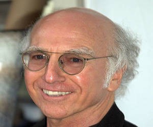 Larry David wearing glasses with white hair on sides of head
